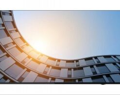 Lenovo ThinkVision 65 tuuman 4K-näyttö, jossa auringonvaloa heijastava moderni kaareva rakennus taustakuvana.